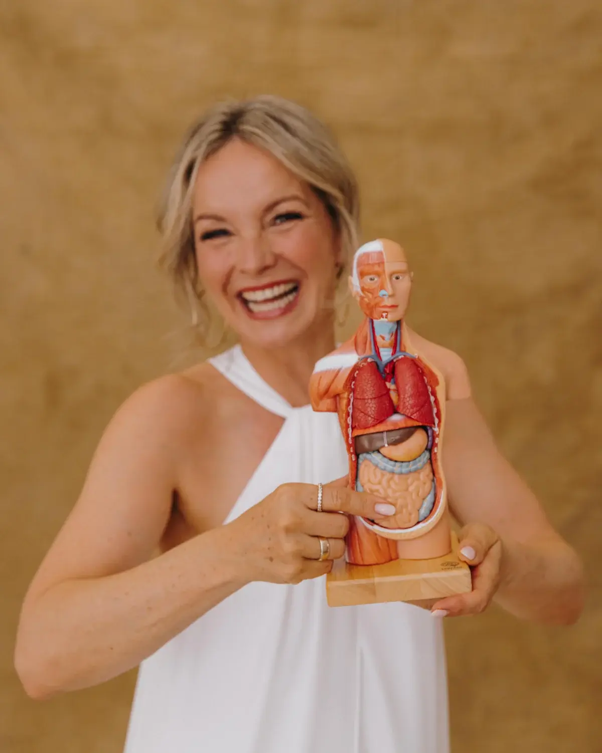 Korinna Söhnholz lacht und hält ein anatomisches Torsomodell in den Händen