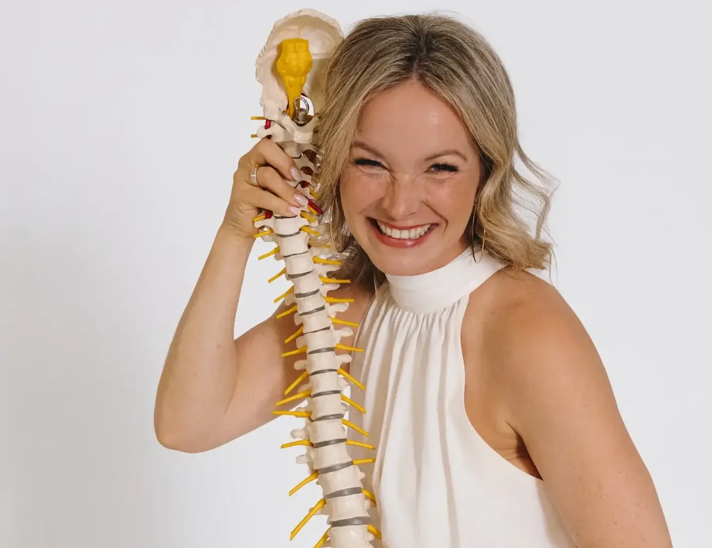 Korinna Söhnholz lacht und hält ein Modell der Wirbelsäule