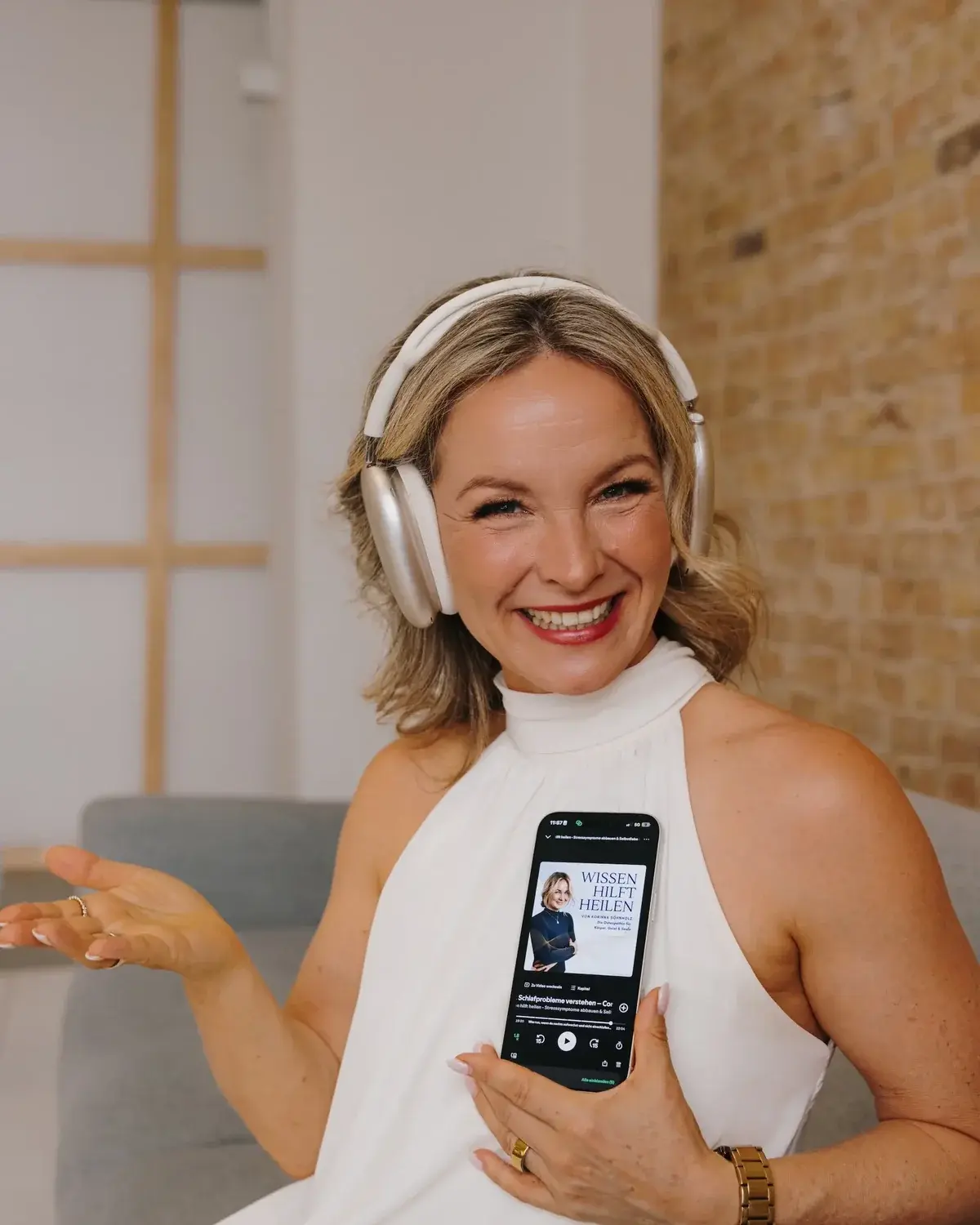 Korinna Söhnholz mit Kopfhörern, in der Hand ein Smartphone mit der Podcast-Folge