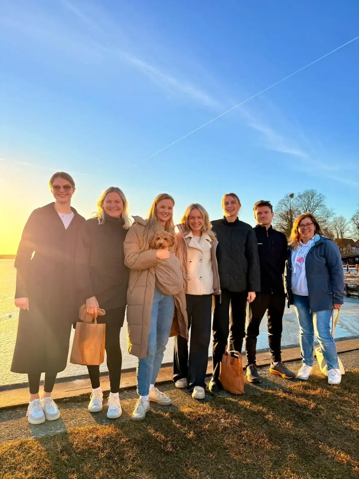Das Team steht bei Sonnenuntergang nebeneinander am Ufer