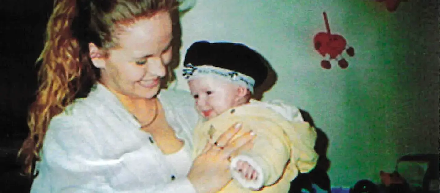 Korinna als junge Mutter mit ihrem Baby auf dem Arm